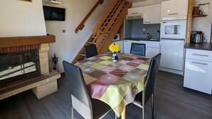 Een kleine keuken met een eethoek, een open haard en een trap.