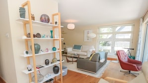 A living room with a wooden bookshelf, a grey sofa, a red chair, and a white armchair. - High Banks (Dartmouth)