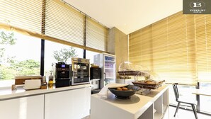 Une cuisine moderne équipée d’une machine à café, d’un réfrigérateur et d’un saladier rempli de fruits posé sur le plan de travail.
