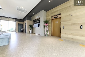 Un hall de hotel con mostrador de recepción, zona de estar y ascensor.