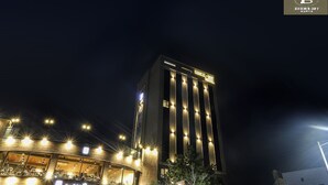 Un grand immeuble d’hôtel, avec des fenêtres illuminées et une enseigne « Caffs Bene » à sa base.