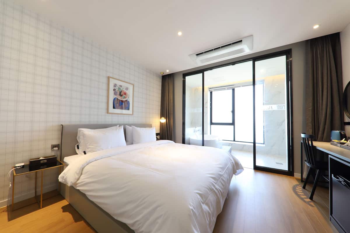 Habitación de hotel moderna con una cama grande, un escritorio y una puerta corrediza de vidrio al exterior.