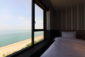 A hotel room with a large window offering a view of the beach and ocean. - Brown Dot Hotel Jungja Beach (Ulsan)
