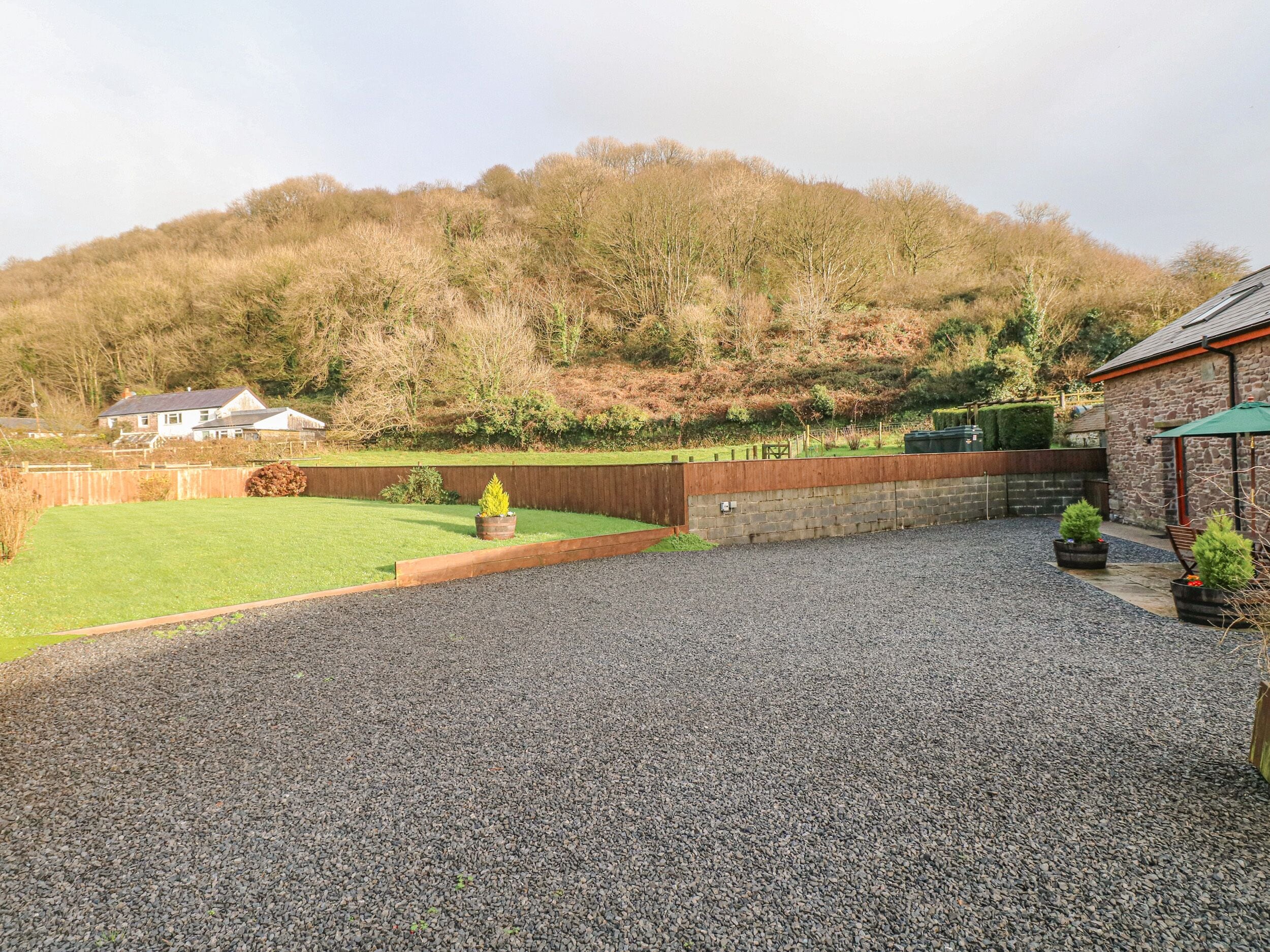 A gravel driveway leading to a house with a stone wall and a wooden fence.