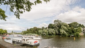 Un muelle a orillas del río con un barco blanco llamado 'Mark Twain' y un barco más pequeño llamado 'Chesterfield'.