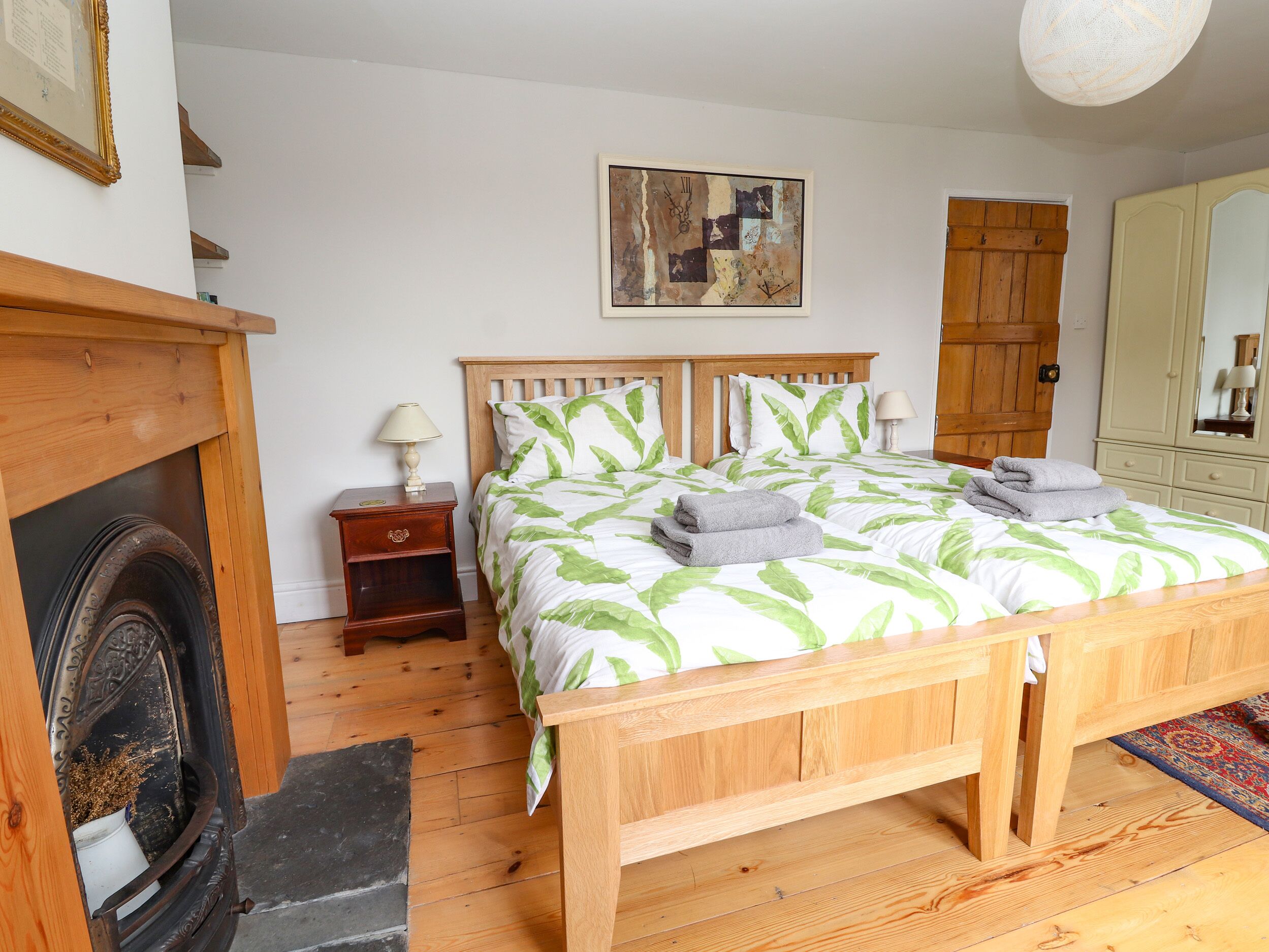 A bedroom with a wooden bed, a nightstand, a painting on the wall, and a wardrobe.