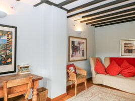 Una sala de estar acogedora con una mesa de madera, sillas de mimbre, un sofá rojo y cuadros en las paredes.