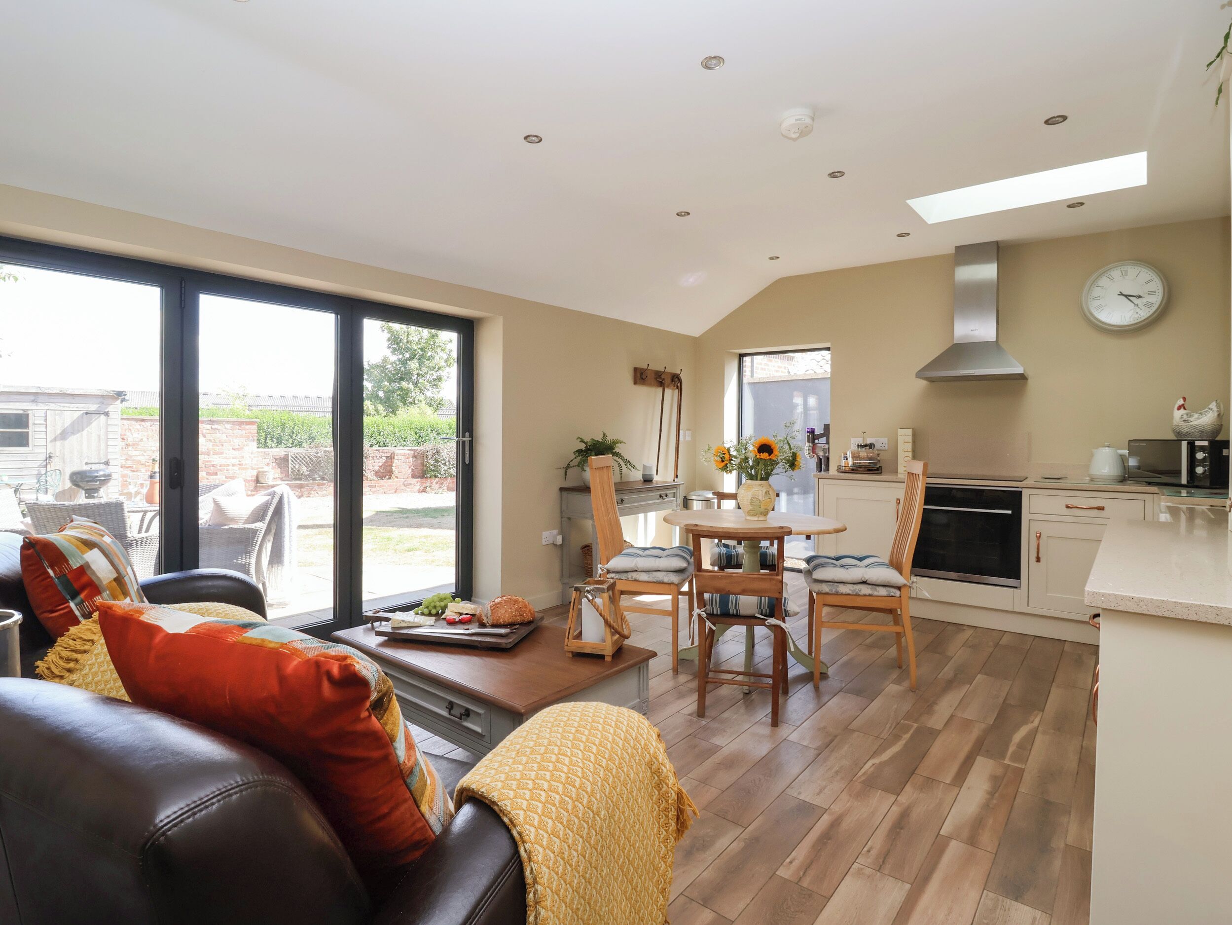 A modern kitchen with a dining area, large windows, and a view of the outdoors.