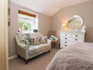 Un dormitorio con sofá, cómoda, silla y ventana con vistas a zonas verdes.