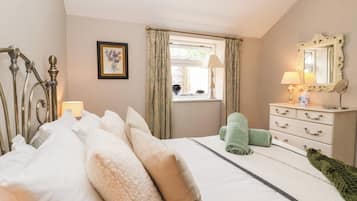 A bedroom with a bed, a dresser, a window with curtains, a mirror, and a framed picture on the wall.