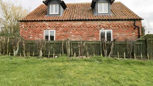 A two-story brick house with a tiled roof, two dormer windows, and a wooden fence in front. - Pipistrelle Cottage (Beverley)