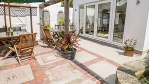 An outdoor patio with a table and chairs, a potted plant, and a wooden pergola. - Lanapoule (Salcombe)