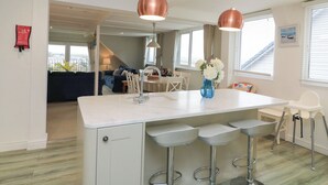 A modern kitchen with a central island, bar stools, and pendant lighting. - Lanapoule (Salcombe)