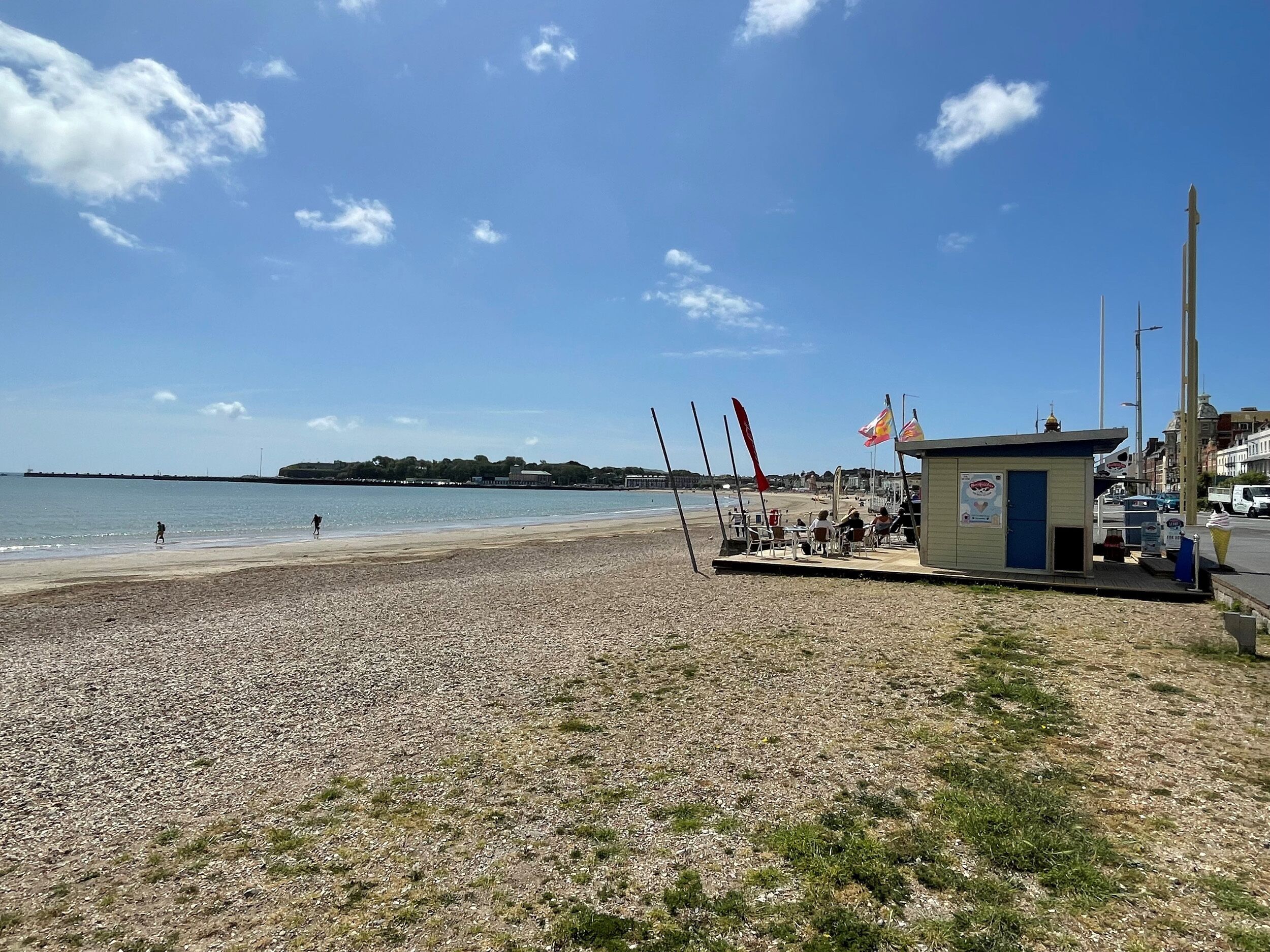 En strand med en lille kiosk, flag og en klar himmel.
