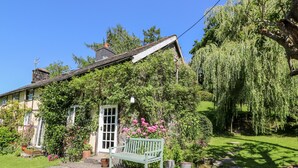 Ein Haus mit Garten, einer Bank und einem Weg.