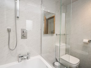 Une salle de bain moderne avec une douche à parois de verre, une baignoire blanche et des toilettes.
