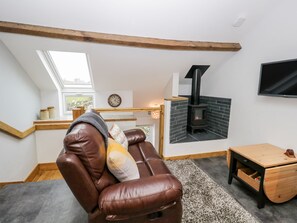 A cozy living room with a leather sofa, a fireplace, a TV, and a wooden table.