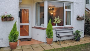 A white house with a front door, a bench, and potted plants. - Fairview (Salcombe)