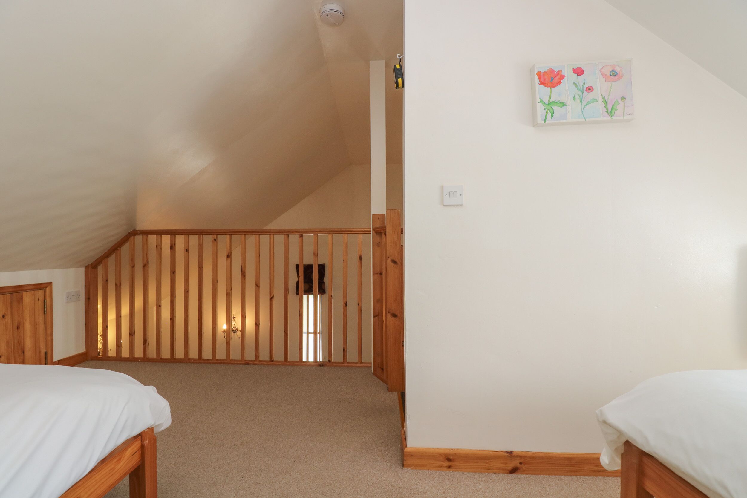 Une chambre avec un plafond en pente, un plancher en bois et un tableau accroché au mur.