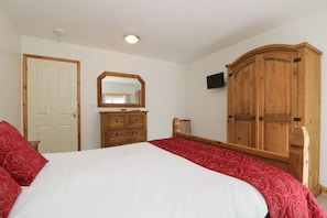 Un dormitorio con una cama grande, un armario de madera, un aparador y un espejo.