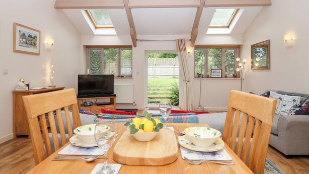 A cozy living room with a dining table, chairs, a television, and a sofa.