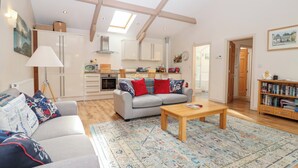 A spacious living room with a grey sofa, a coffee table, and a patterned rug.