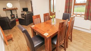 Un comedor con una mesa y sillas de madera, una chimenea, un sofá y un televisor.