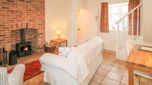 A cozy room with a brick fireplace, a bed, a table, and a window with curtains.