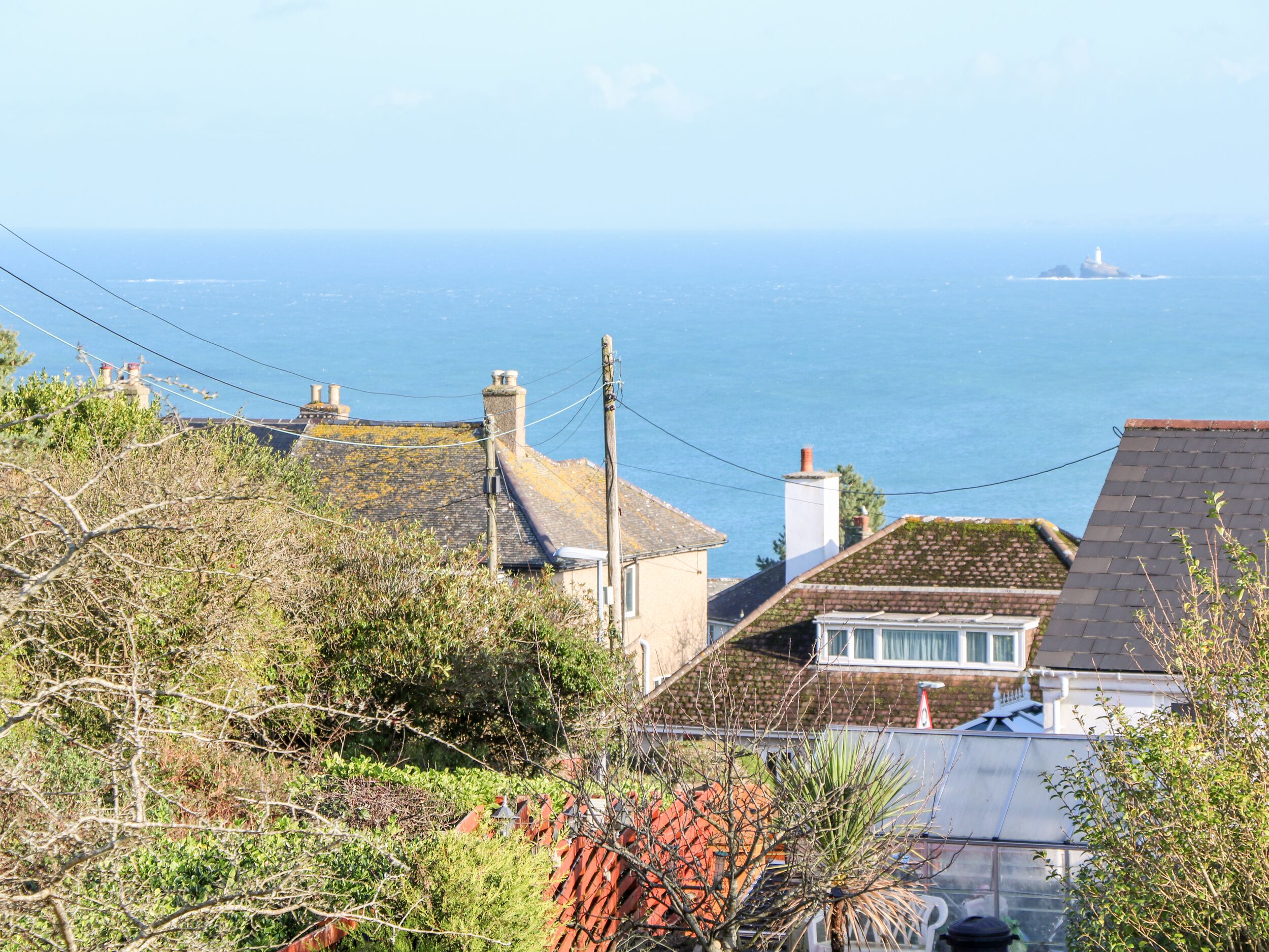 A coastal residential area with houses, a lighthouse, and a clear view of the sea.
