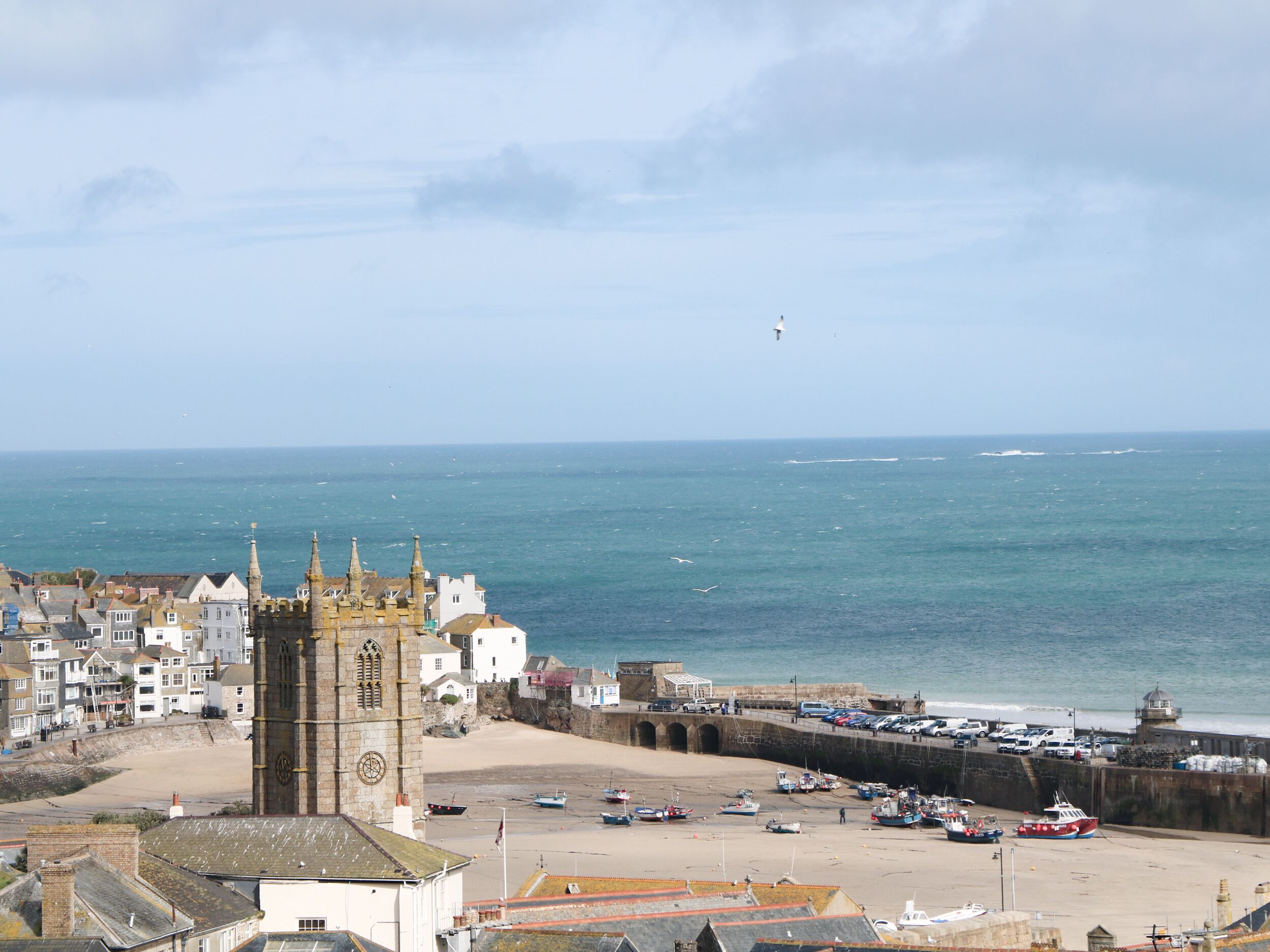 A coastal town with a prominent tower, a sandy beach, and a sea view.