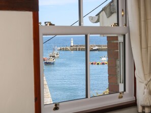 Blick durch ein Fenster auf einen Hafen mit Booten und einem Leuchtturm.