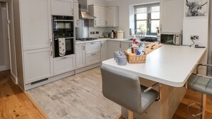 Une cuisine moderne avec des armoires blanches, un four encastré, un micro-ondes et un grand îlot central doté de tabourets de bar.