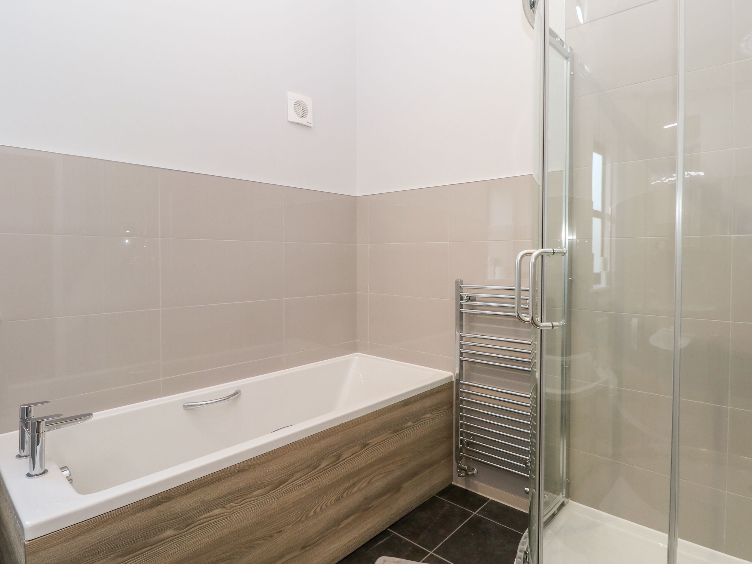 Un baño moderno con una bañera independiente, cabina de ducha con paredes de vidrio y un perchero para toallas.