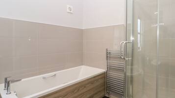 Un baño moderno con una bañera independiente, cabina de ducha con paredes de vidrio y un perchero para toallas.