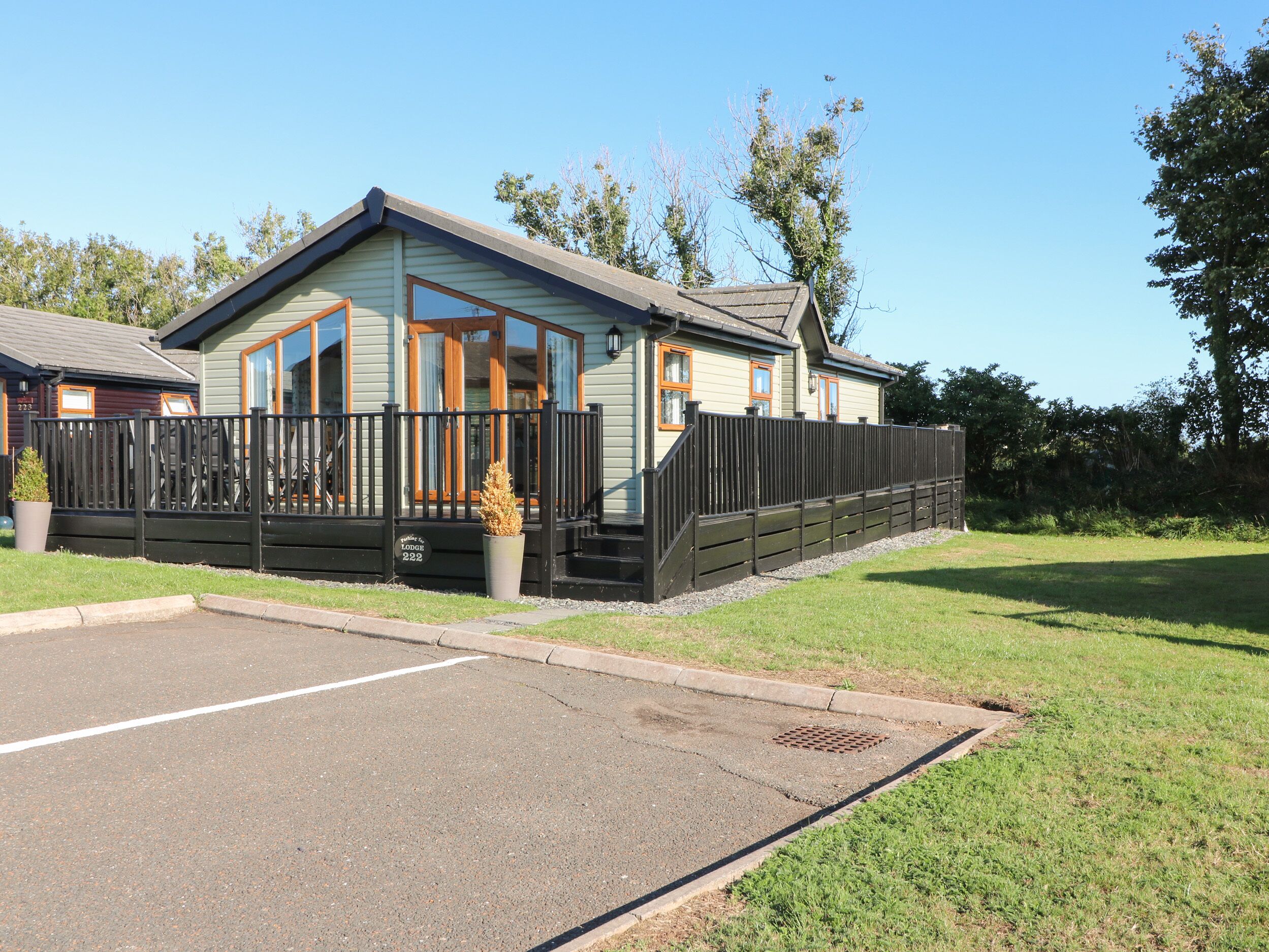 A lodge with a fenced patio, a covered entrance, and a grassy area in front.