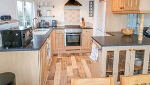 Une cuisine avec des meubles de rangement en bois, une cuisinière, un évier et une fenêtre.