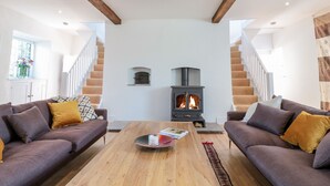 A living room with two sofas, a coffee table, and a wood-burning stove. - Carriage House (Presteigne)