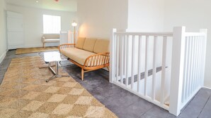 A modern living room with a sofa, a coffee table, a rug, and a white railing. - Carriage House (Presteigne)