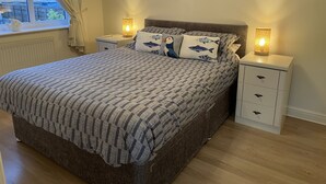 A neatly arranged bedroom with a patterned bedspread, two bedside lamps, and a wall decoration. - Seagull Cottage (Holyhead)