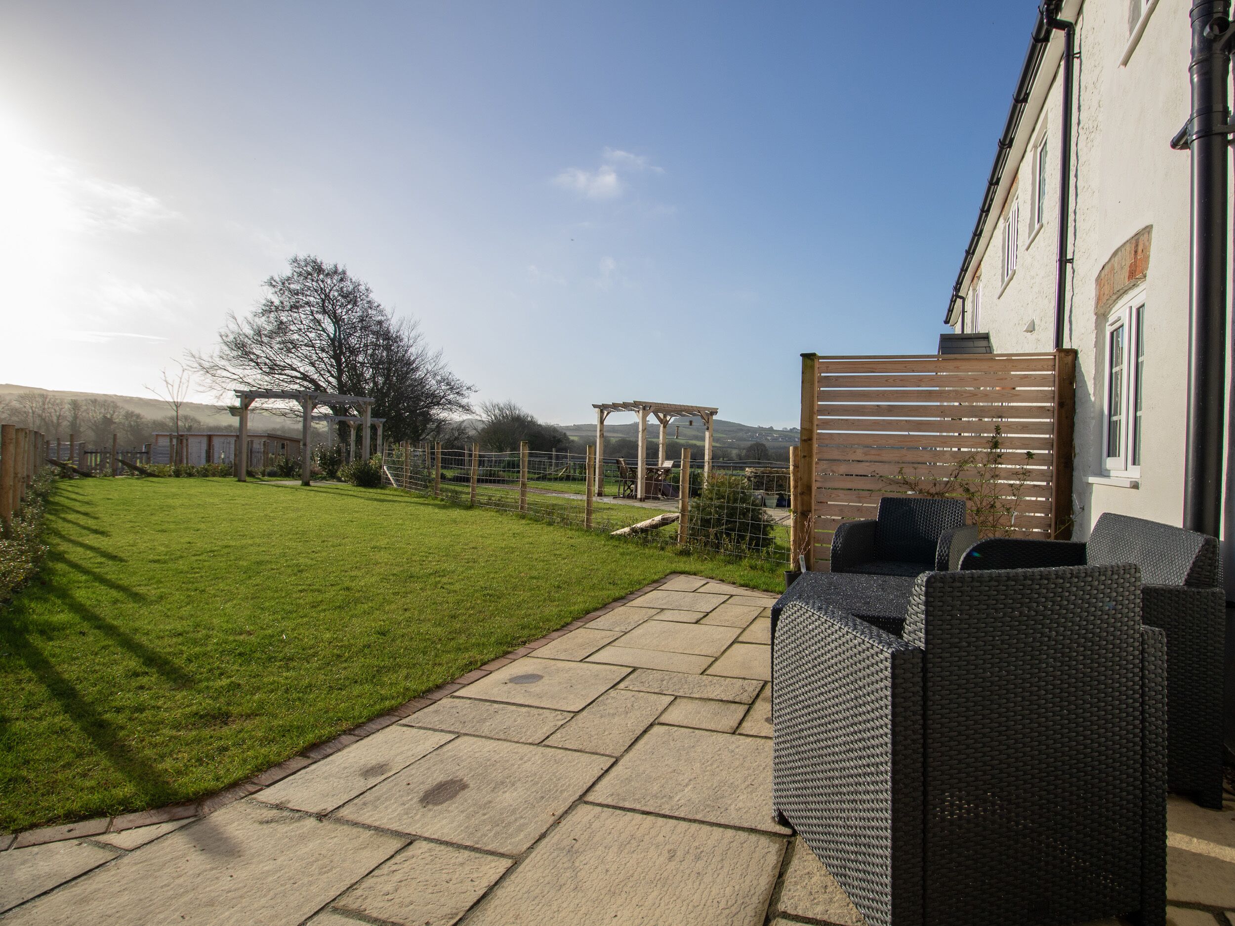 A patio with outdoor furniture, a grassy lawn, and a view of the countryside.