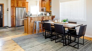 Une cuisine dotée de meubles en bois, d’appareils électroménagers en acier inoxydable et d’un coin repas avec une table et des chaises.