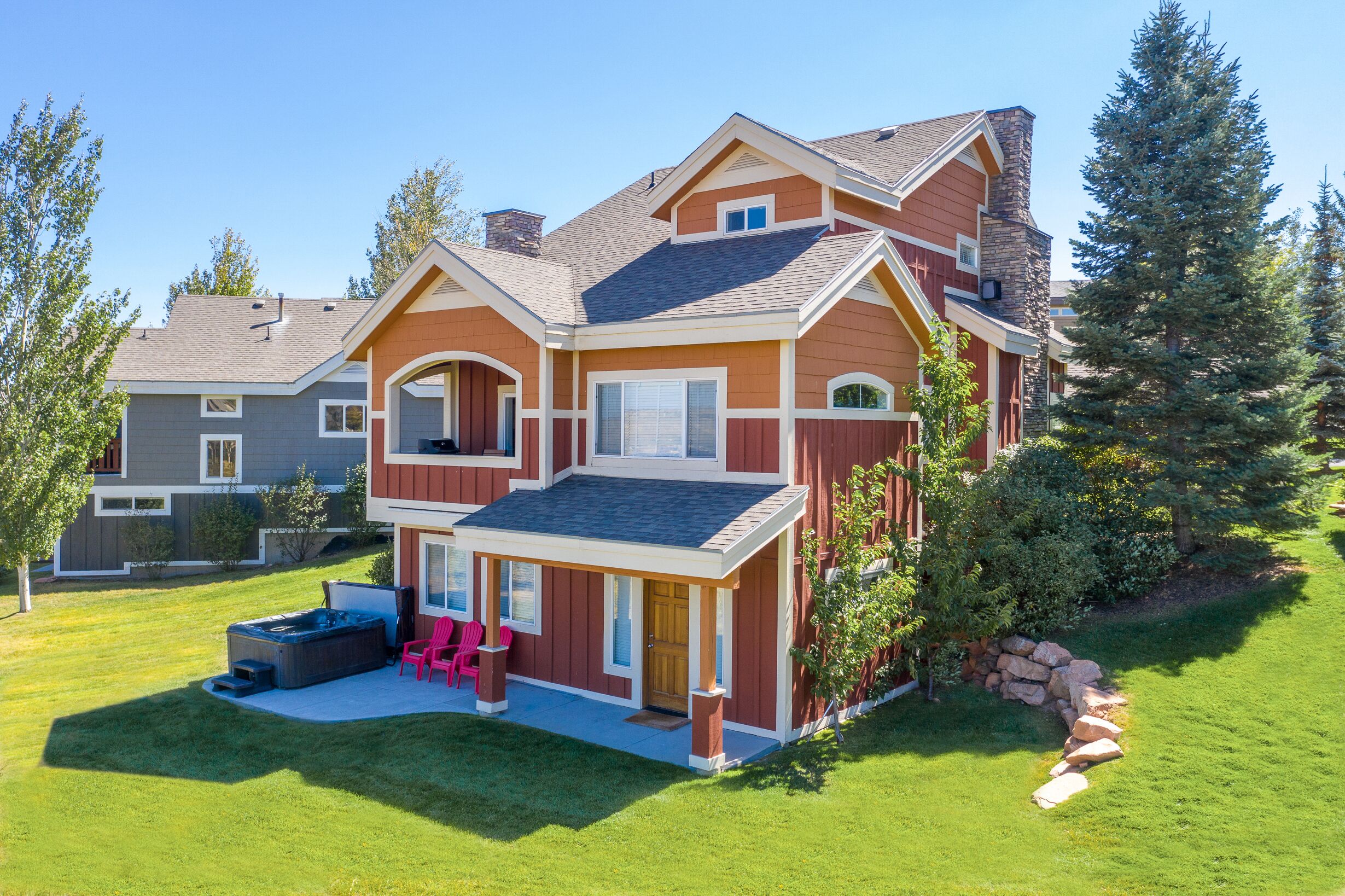 A two-story house with a patio, hot tub, and outdoor seating.