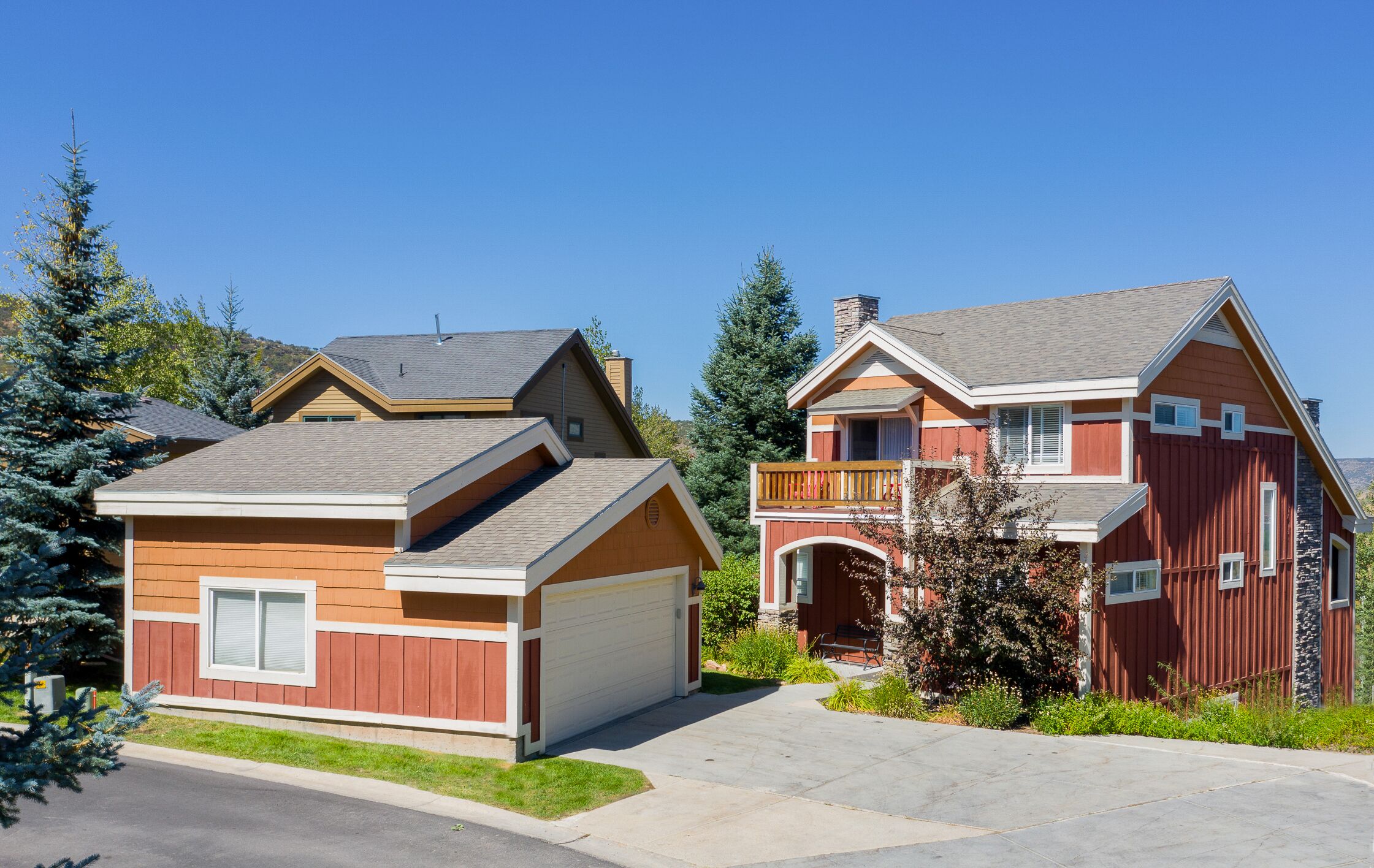 A two-story house with a garage, a balcony, and a chimney.