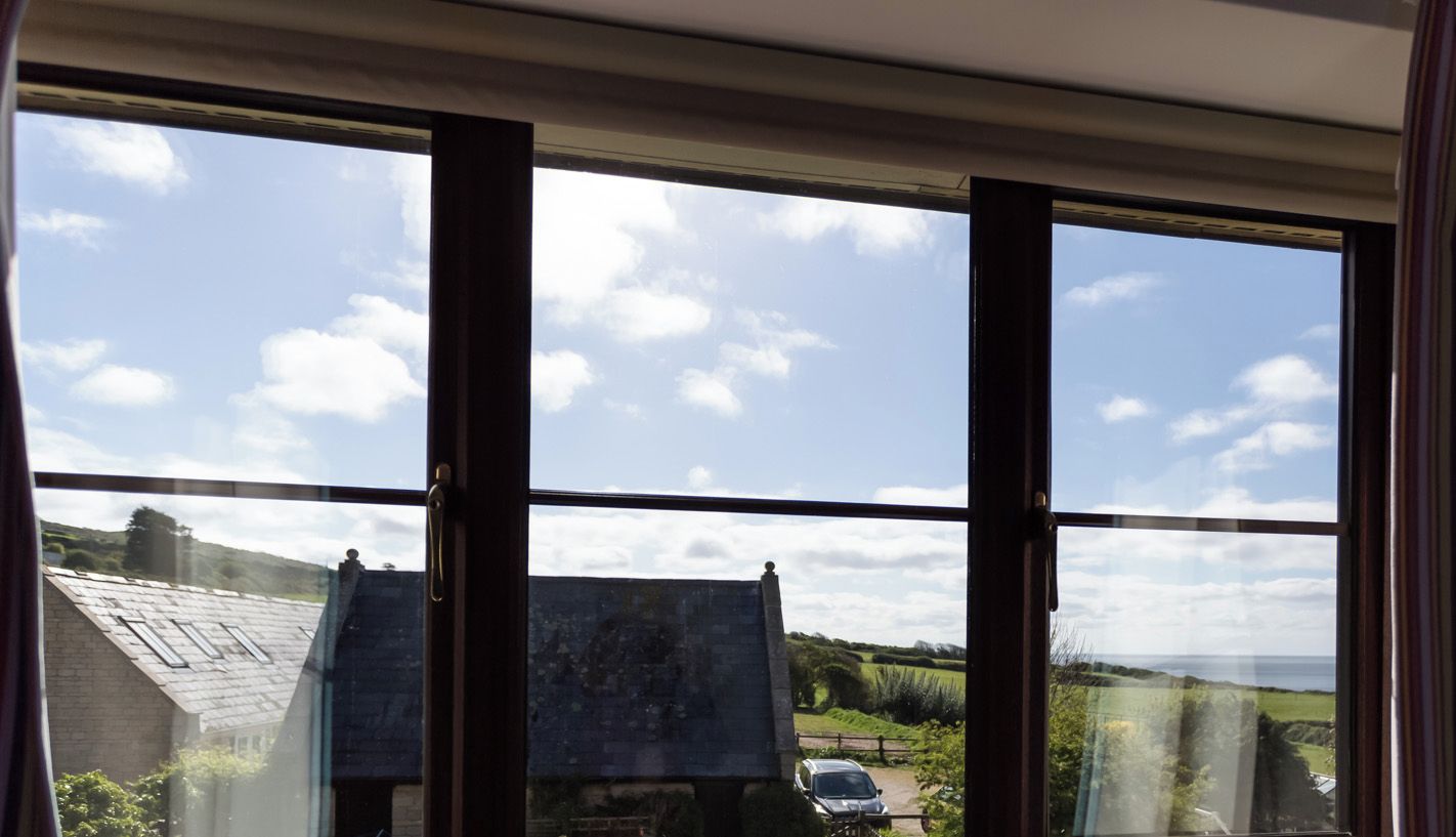 A room with a large window overlooking a rural landscape, including a house and fields.