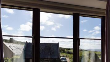 A room with a large window overlooking a rural landscape, including a house and fields.