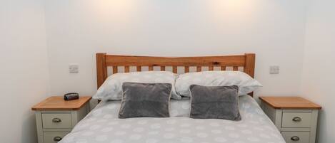 A bed with a wooden headboard, two bedside tables, and two wall-mounted lamps.