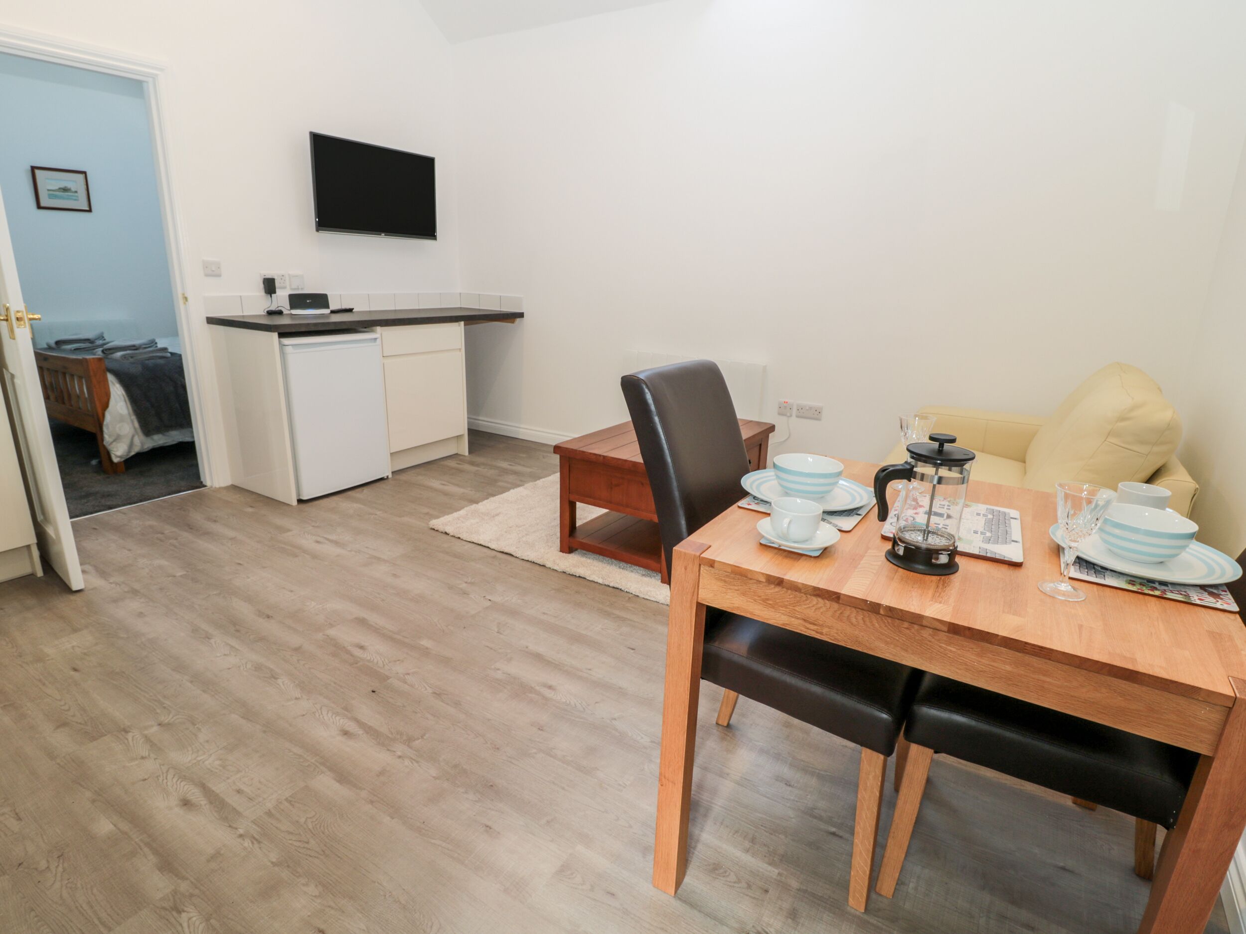 Ett kompakt bostadsutrymme med ett litet kök, en matplats och en soffa.