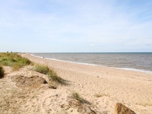 Ein sandiger Strand mit sanften Wellen und blauem Himmel.