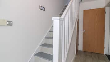 A staircase with white railings and grey steps leading to a wooden door.