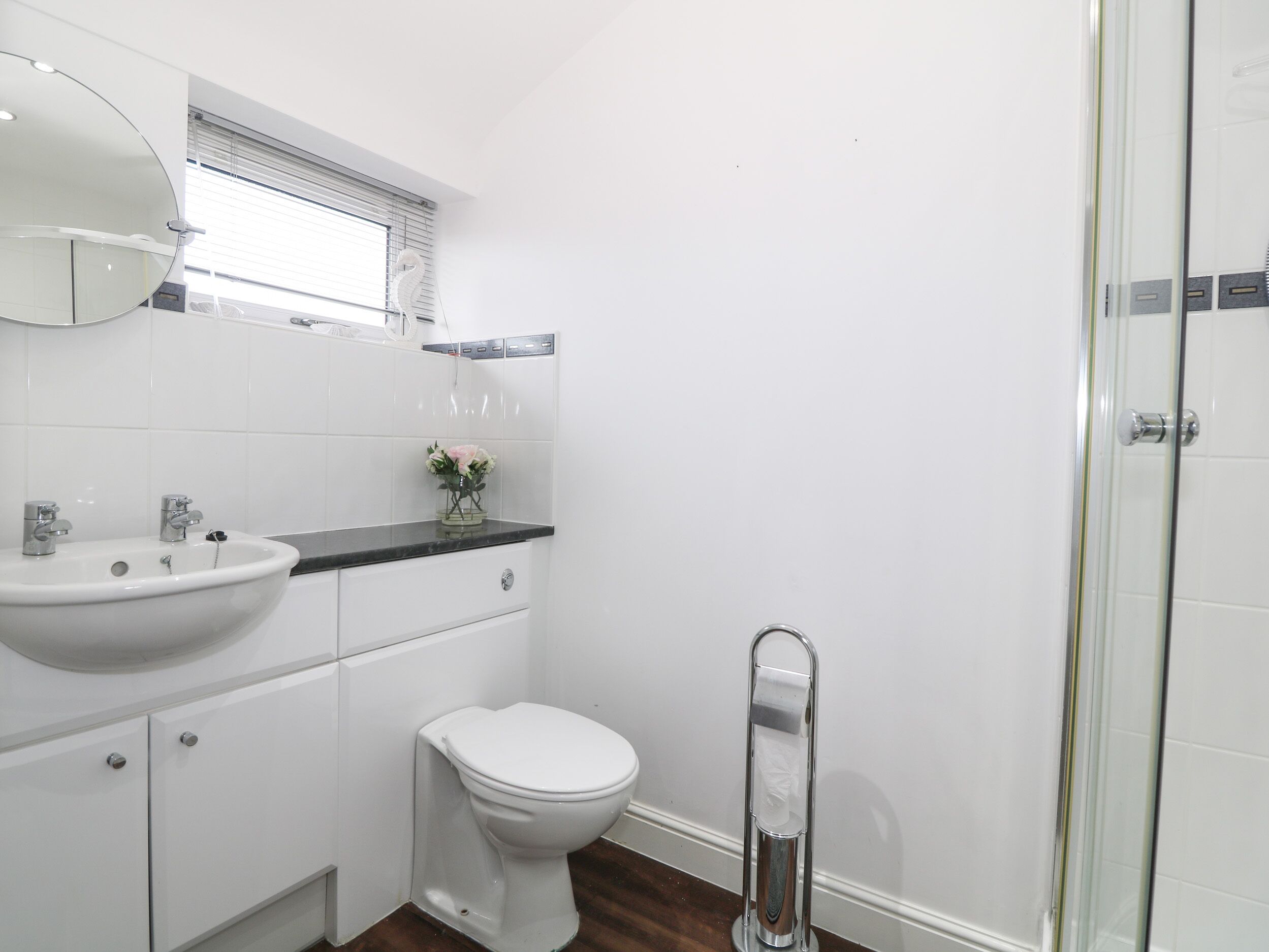 A modern bathroom with a white sink, toilet, and shower.